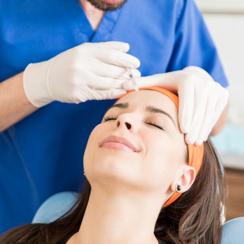 A woman smiles as she receives botox from her dentist - naccid buford dentist, GA